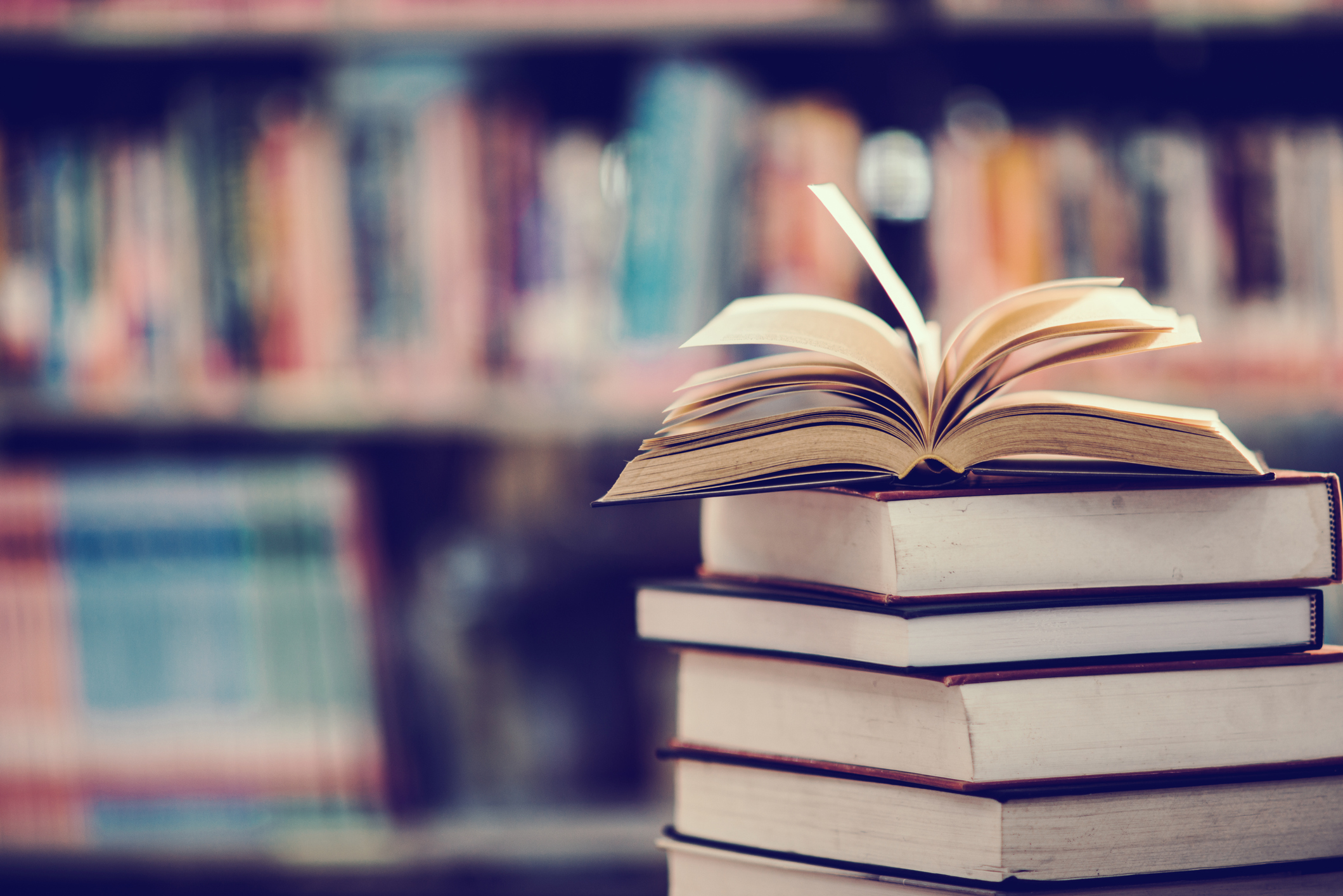 Books On Table Against Shelf In Library