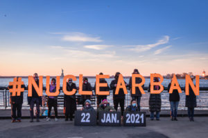 BROOKLYN, NY, UNITED STATES - 2021/01/10: Participants holding illuminated letters that read #NUCLEARBAN. Activists from New York-based direct action group Rise and Resist and the International Campaign to Abolish Nuclear Weapons (ICAN) took to the streets to announce the entry into force of the Treaty on the Prohibition of Nuclear Weapons on January 22, 2021 by holding illuminated letters that read #NUCLEARBAN in front of iconic New York landscapes.