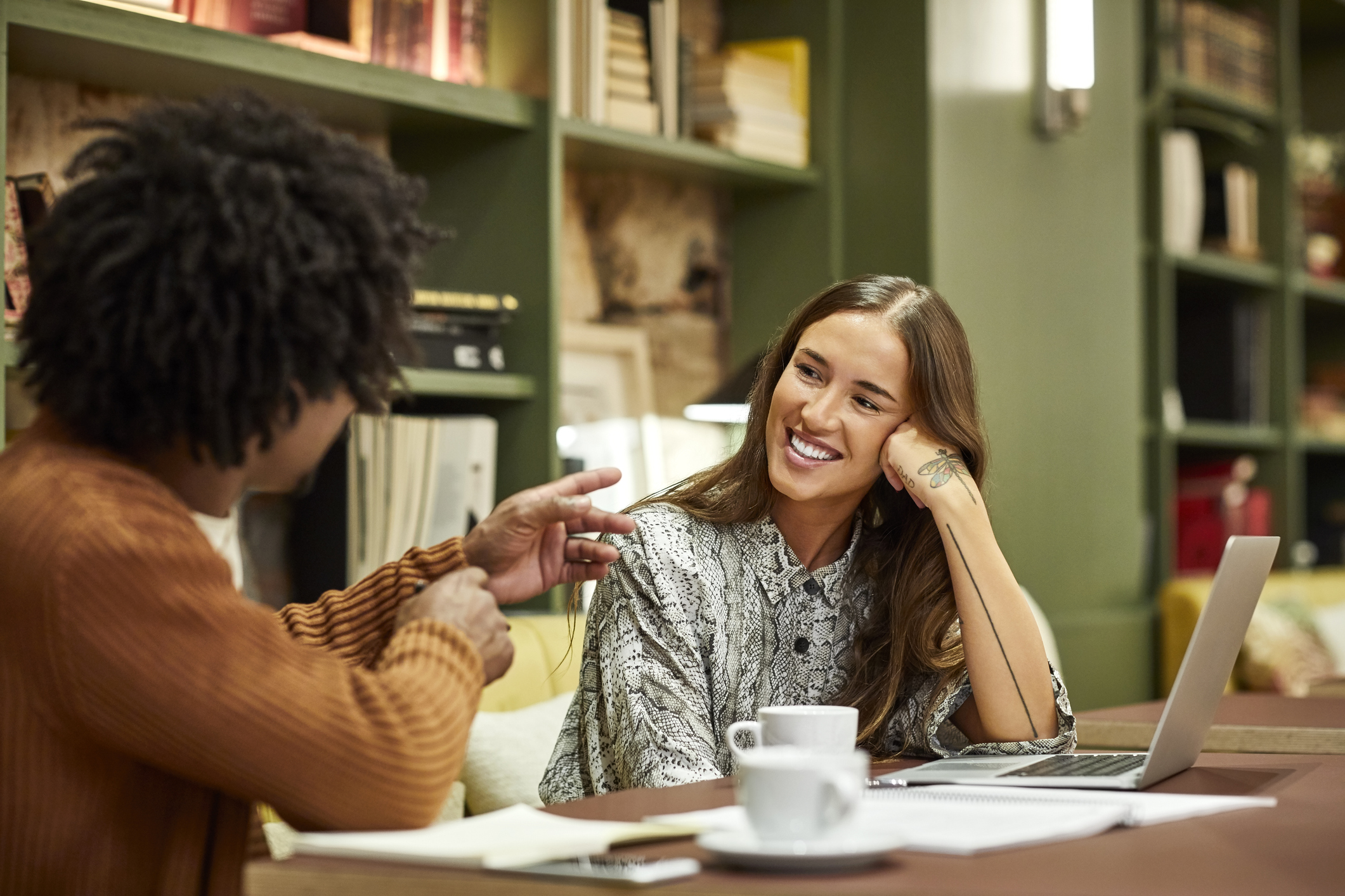 Smiling businesswoman listening to businessman at desk.