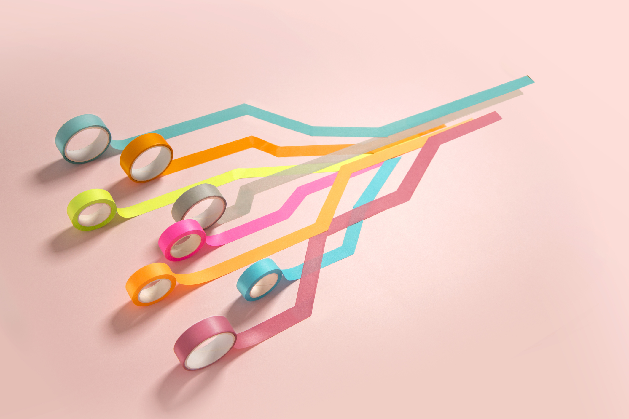 A group of coloured strip rolling, united, towards one direction on pink background.