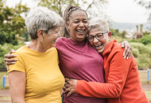 Happy senior women having fun together outdoor - Elderly generation people hugging each other at park