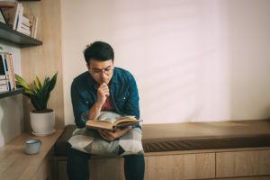 Man sitting on sofa reading book at home