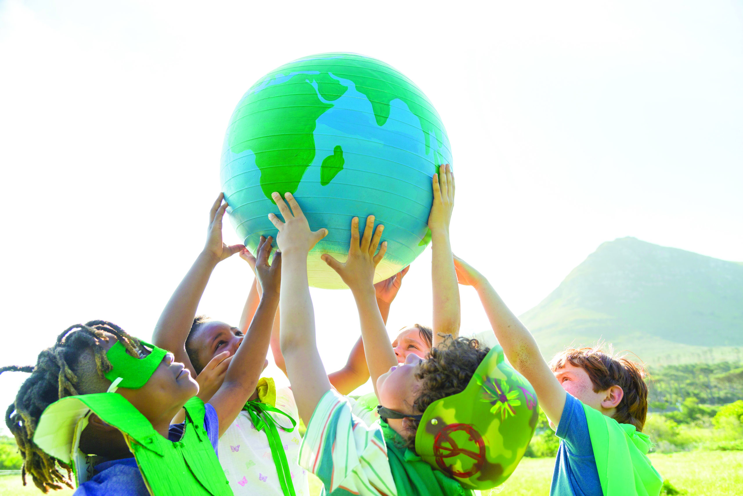 Group of children holding up a balloon of the world.