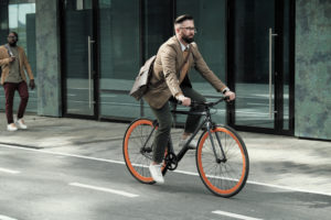 Businessman riding to his work by bike along the streets in the city